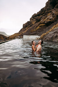 Couple laughing in water between mountains
