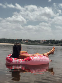 Young woman relaxing on inflatable ring over lake