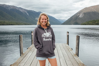 Portrait of smiling young woman standing on pier