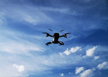 Low angle view of silhouette airplane flying against blue sky