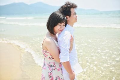 Side view of woman embracing boyfriend at beach