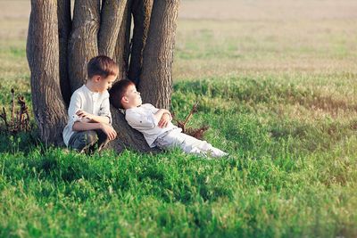 Father and son sitting on grassy field