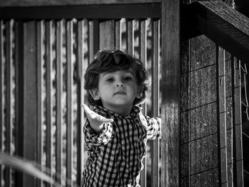 Portrait of cute baby boy standing by railing