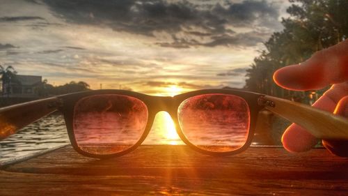 Close-up of sunglasses against sky at sunset