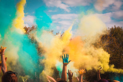 People playing with powder paints against sky