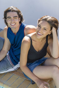 Portrait of happy couple sitting at poolside