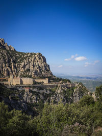 Scenic view of castle and mountains against blue sky