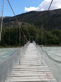 Footbridge over mountain against sky