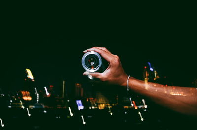 Double exposure of cropped hand holding lens with cityscape