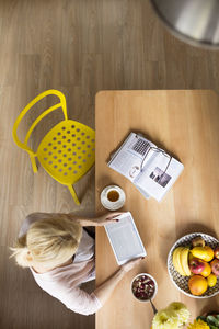 High angle view of woman using tablet computer while sitting at table