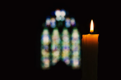 Close-up of illuminated candle in darkroom