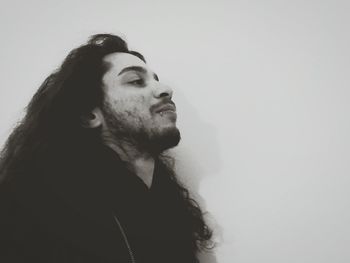 Side view of man with long hair against wall