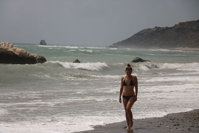 Full length of shirtless man on beach against sky