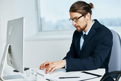 Young woman using phone while sitting on table