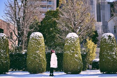 Rear view of woman walking on snow covered tree