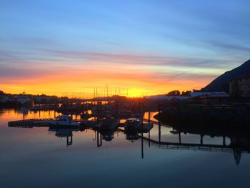 Silhouette harbor in river against sky during sunset