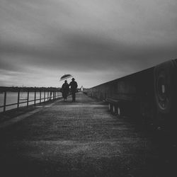 People walking on road against cloudy sky