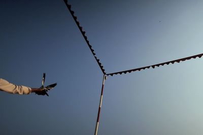 Low angle view of man flying against clear blue sky