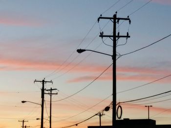 Low angle view of silhouette electricity pylon against sky during sunset