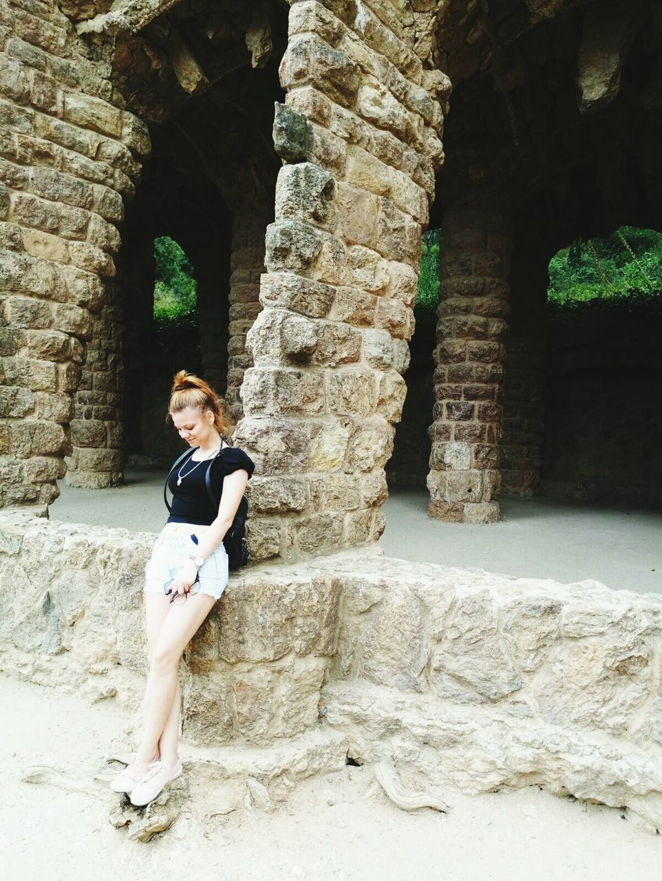real people, young women, one person, young adult, architecture, lifestyles, arch, looking at camera, leisure activity, full length, built structure, day, rock - object, portrait, casual clothing, standing, front view, posing, sitting, beautiful woman, outdoors, architectural column, old ruin, smiling, building exterior, women