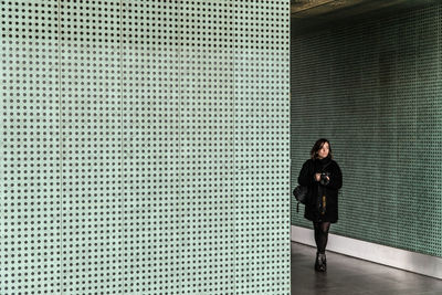 Full length of woman standing against wall of building
