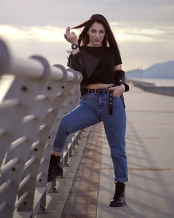 Portrait of young woman standing against sky