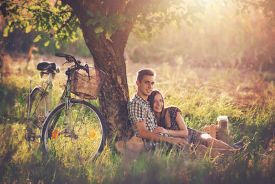 Portrait of smiling friends sitting on grassy field at park