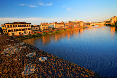 Buildings by lake against blue sky