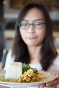 Close-up of woman holding food in plate at home