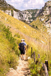 Rear view of man walking on footpath