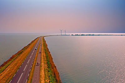 Scenic view of road in sea against sky during sunset