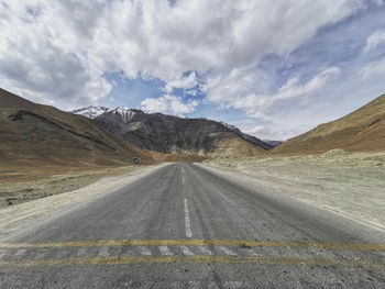 Scenic view of road by mountains against sky