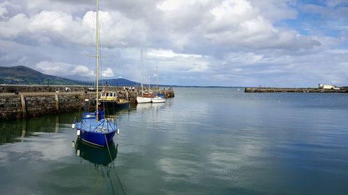 Boats in sea against cloudy sky