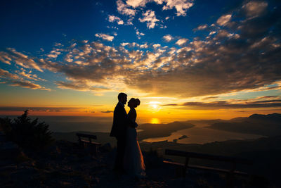 Couple standing against sky during sunset