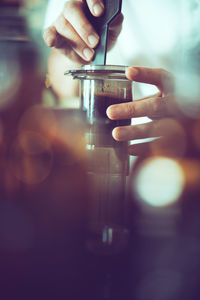 Close-up of hand making coffee in cafe