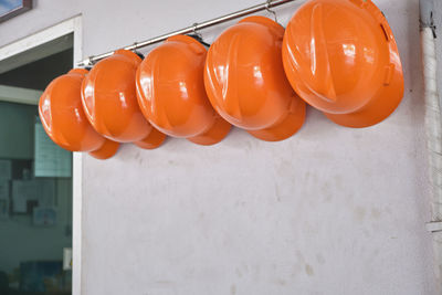 Close up hard hats hanging on hook against the dirty white wall.