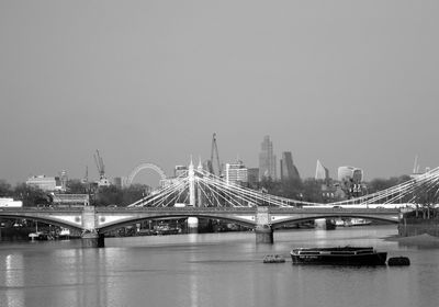 Bridge over river against sky in city