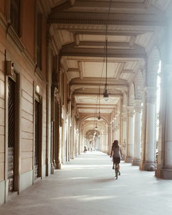 Rear view of woman cycling in colonnade