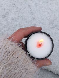 Cropped hand of woman holding lit tea light during winter