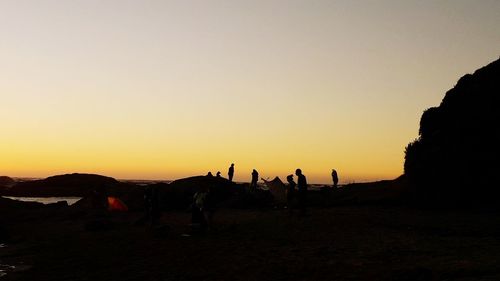 Silhouette people on land against clear sky during sunset