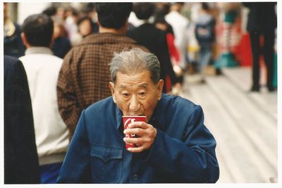 Close-up of senior man having drink in city