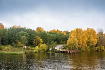 Trees by lake against sky during autumn