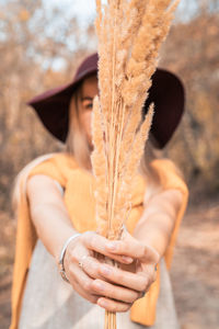 Portrait of woman holding hat standing outdoors