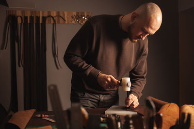 Portrait of handsome tanner man at work, small business, authentic workshop, indoors. knocks