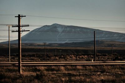 Electricity pylons on mountain against sky