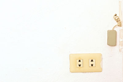 Close-up of telephone booth against white wall