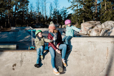 Mom and her kids playing and having fun at a skatepark outside