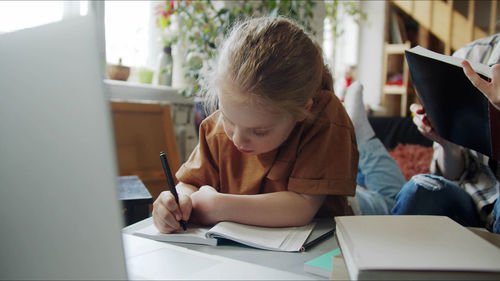 Girl writing in book while studying at home