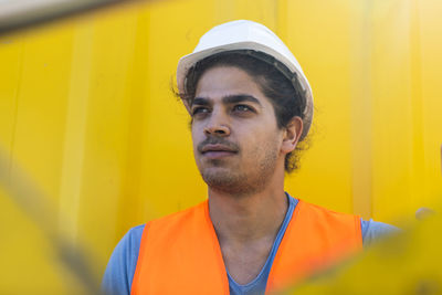 Young engineer working outside with yellow background