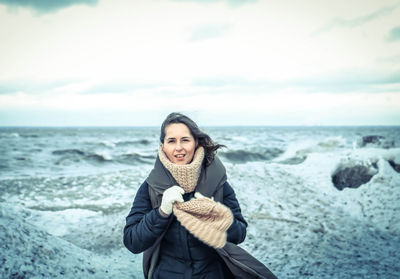 Portrait of woman standing at beach against sky